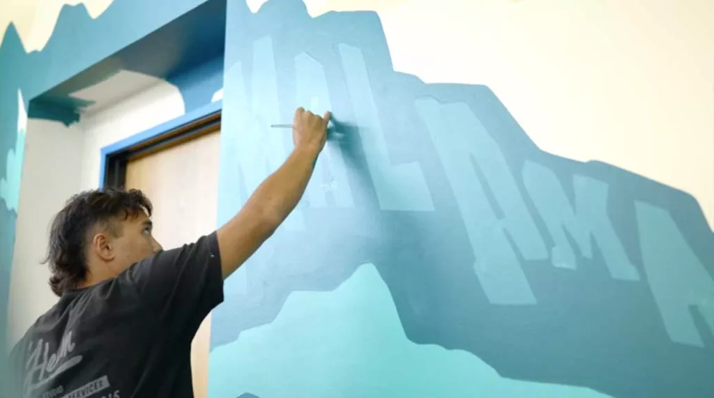 Artist Jack Soren painting a mural at the Malama Solar Office
